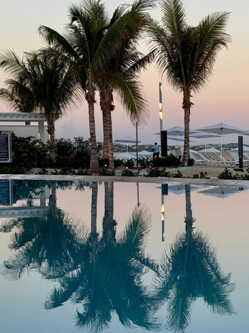 Palm trees reflected in a resort pool at sunset in Turks and Caicos